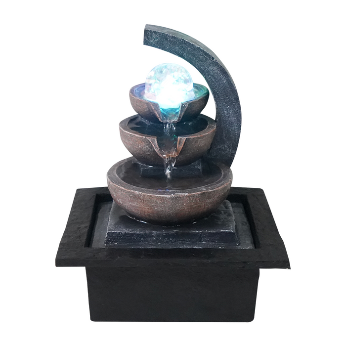 A modern Zen-inspired water feature with a minimalist design, consisting of a series of cascading metal bowls with water flowing from the highest bowl down to the lowest, illuminated by a blue light.