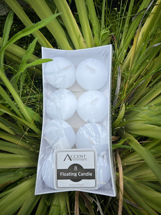 A pack of eight unscented white floating candles presented in a natural setting with greenery in the background.