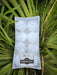 A pack of eight unscented white floating candles presented in a natural setting with greenery in the background.
