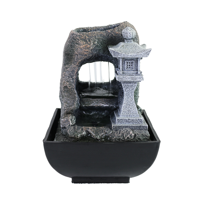 A Zen-inspired water feature with a realistic rockwork and a pagoda, in a black bowl with water flowing down the pagoda.