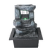 A modern Zen-inspired tiered slab fountain with a sleek, contemporary design and a green light illuminating from the top.