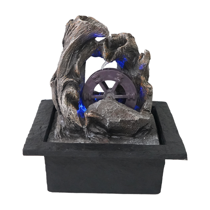 A rustic style Water Mill fountain featuring a metal water wheel in the center with blue water, surrounded by a bed of dark stones and wood details.